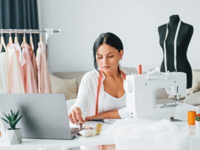 Professional sewing machine. Seamstress is in her office that is with different clothes